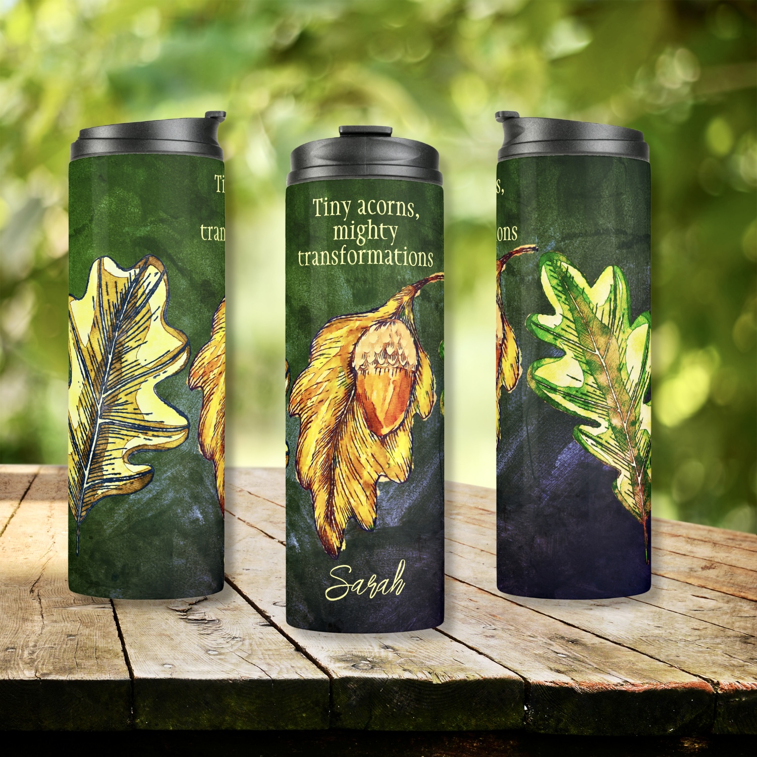 Acorn Fall Colors Inspirational Thermal Tumbler - A bold and vibrant design with lime and golden dry leaves, brilliantly painted golden and orange acorns, arranged as a collage on a dark hunter green washed-out surface. Customizable quote: 'Tiny acorns, mighty transformations' - personalization options available. Two custom fields for personalized messages or names.