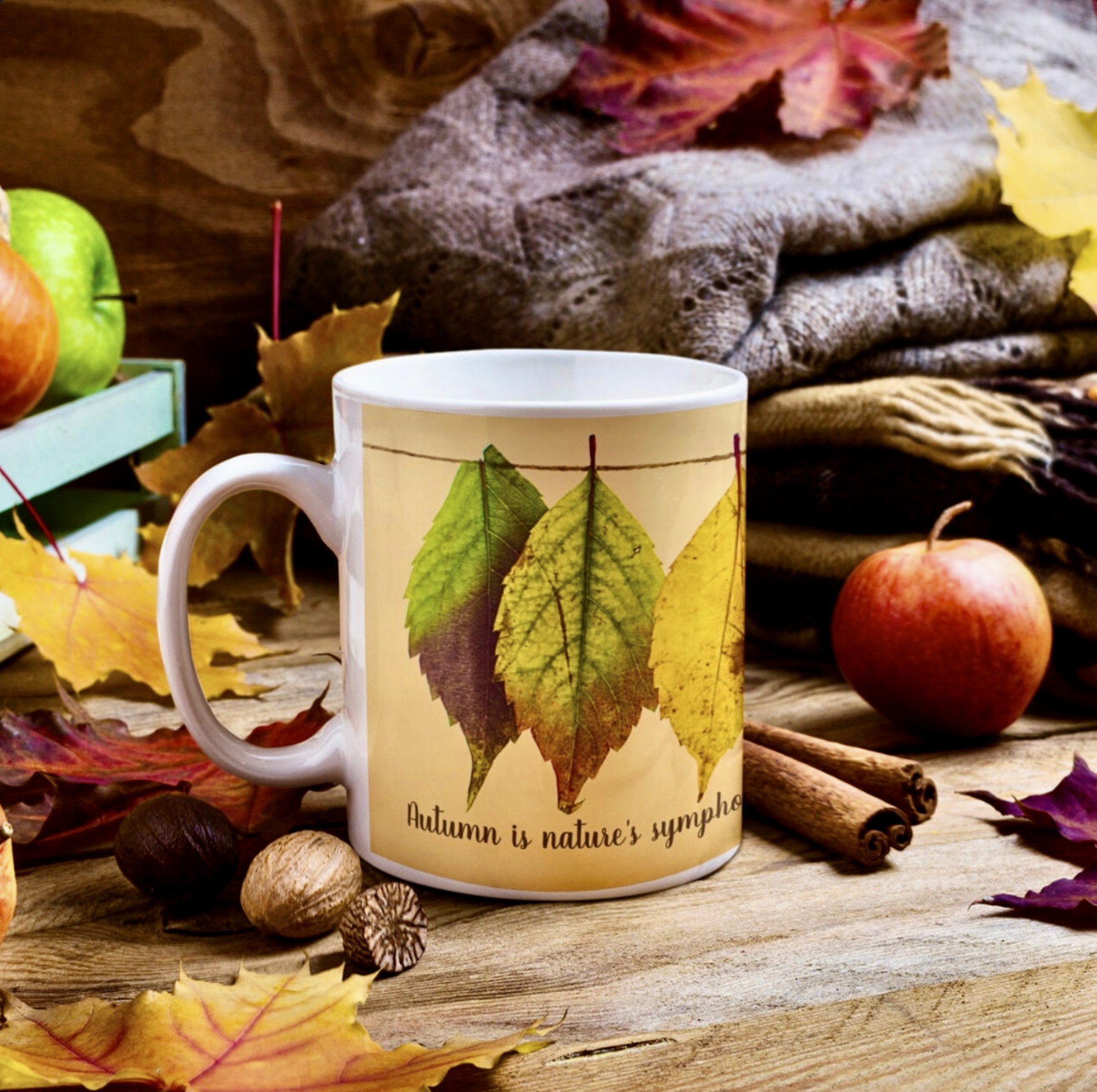 Yellow coffee mug with green dry leaves, surrounded by fall season fruit.