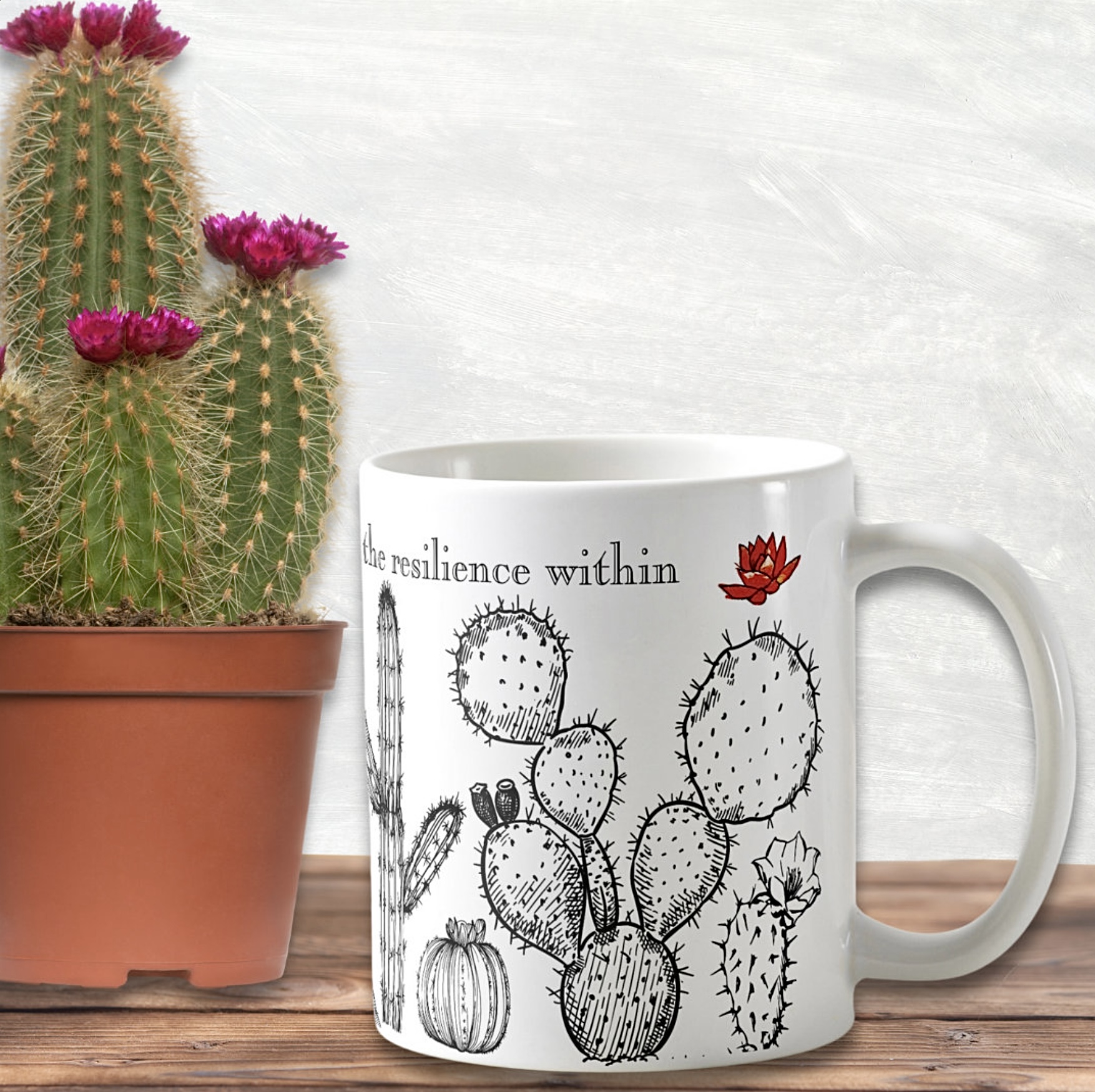 White mug with black cactus drawing and tiny flower. 