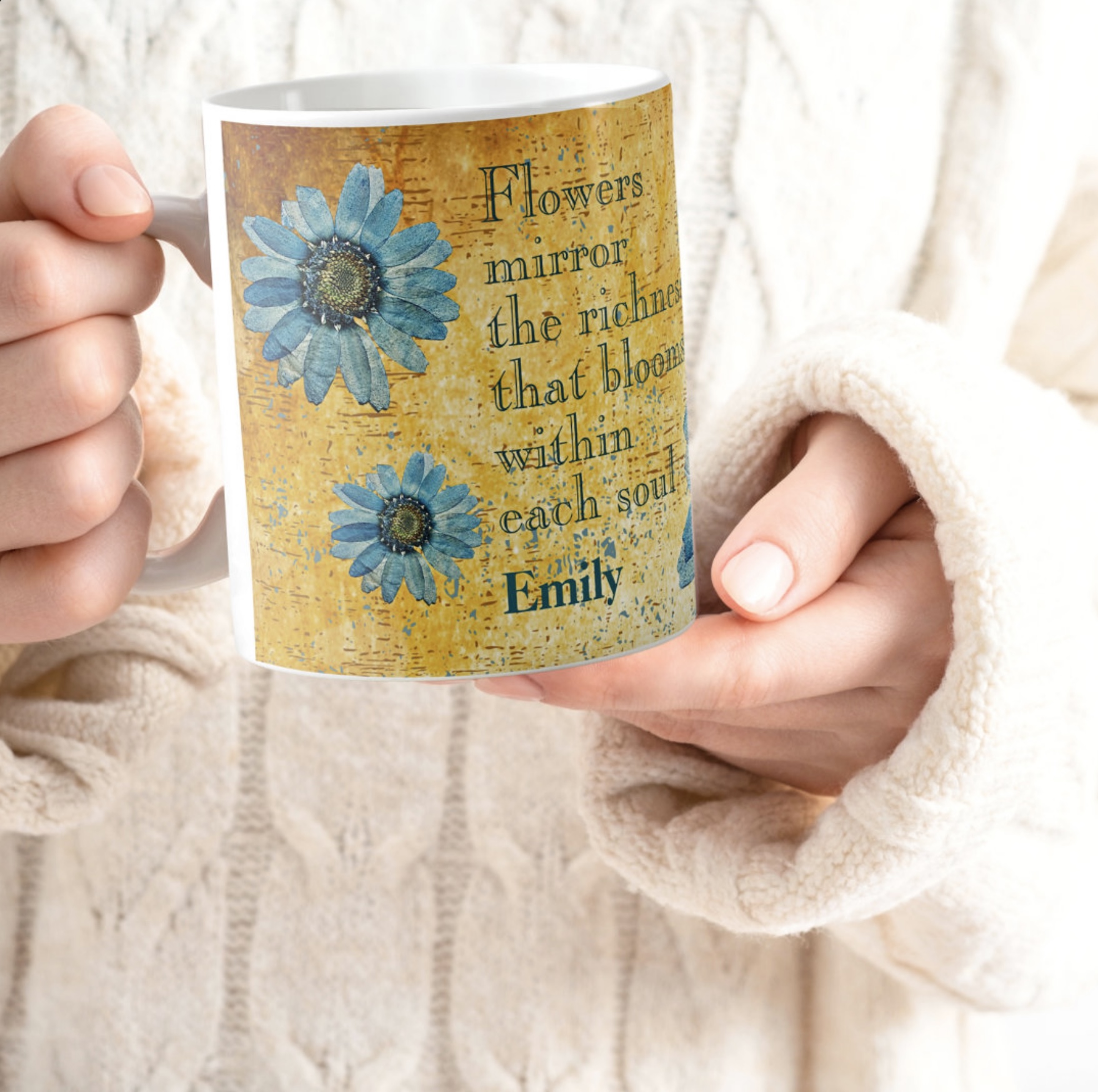 Hands holding a coffee mug with blue gerberas design, with inspirational quote and a orange washed out background.