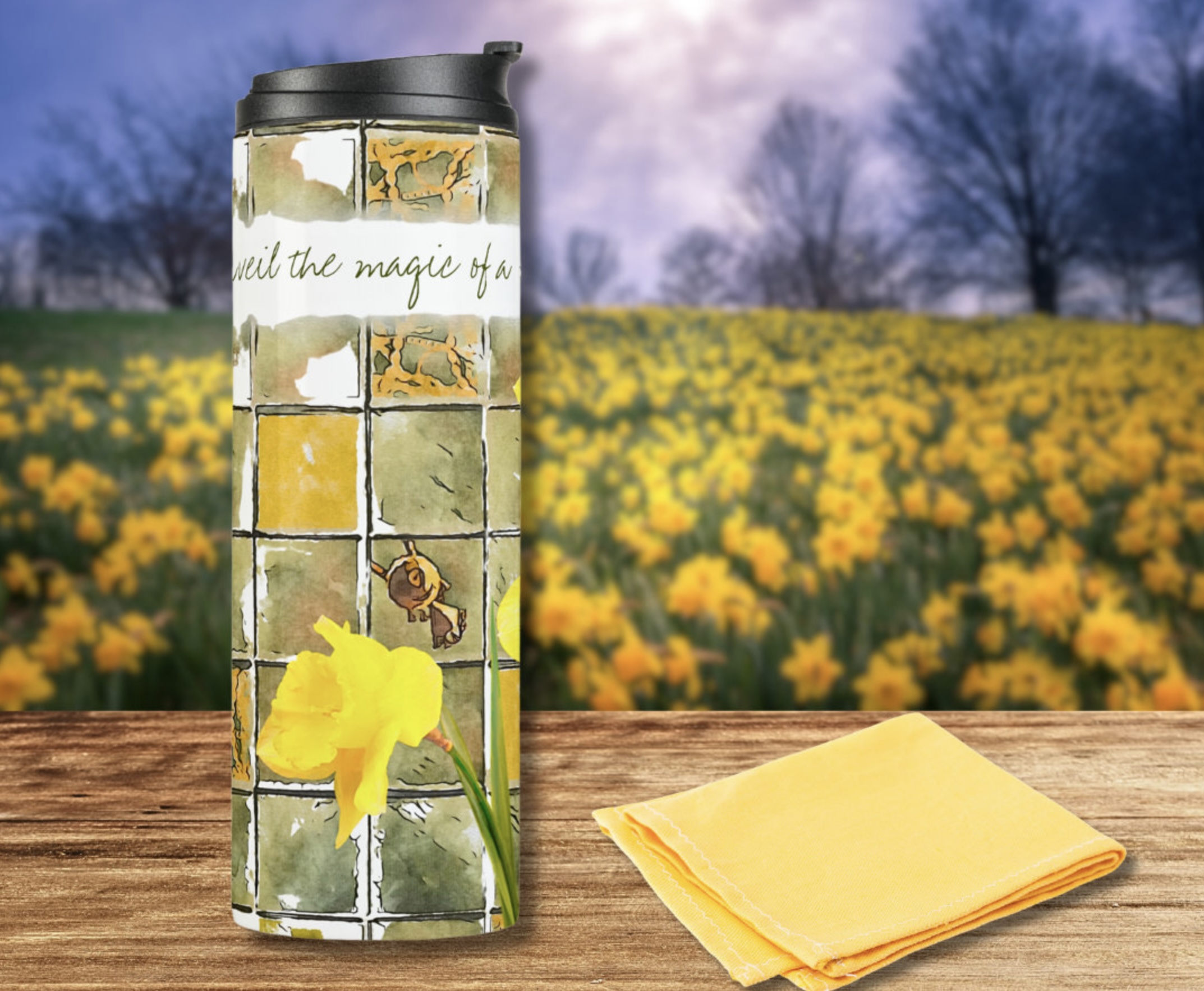 Thermal tumbler with daffodils watercolor illustration on a washed out green background, with this inspirational quote Unveil the magic of a new day and new beginnings.