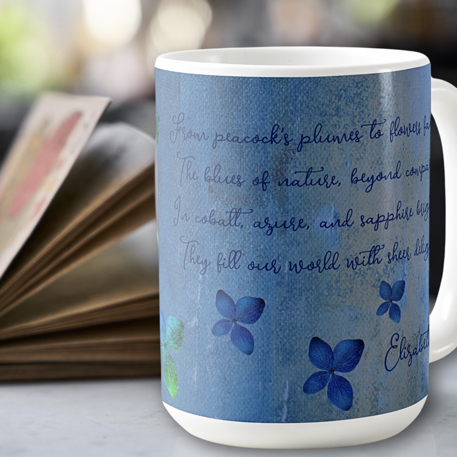 Side view of a coffee mug showing an inspirational message and blue flowers against a washed out blue background.