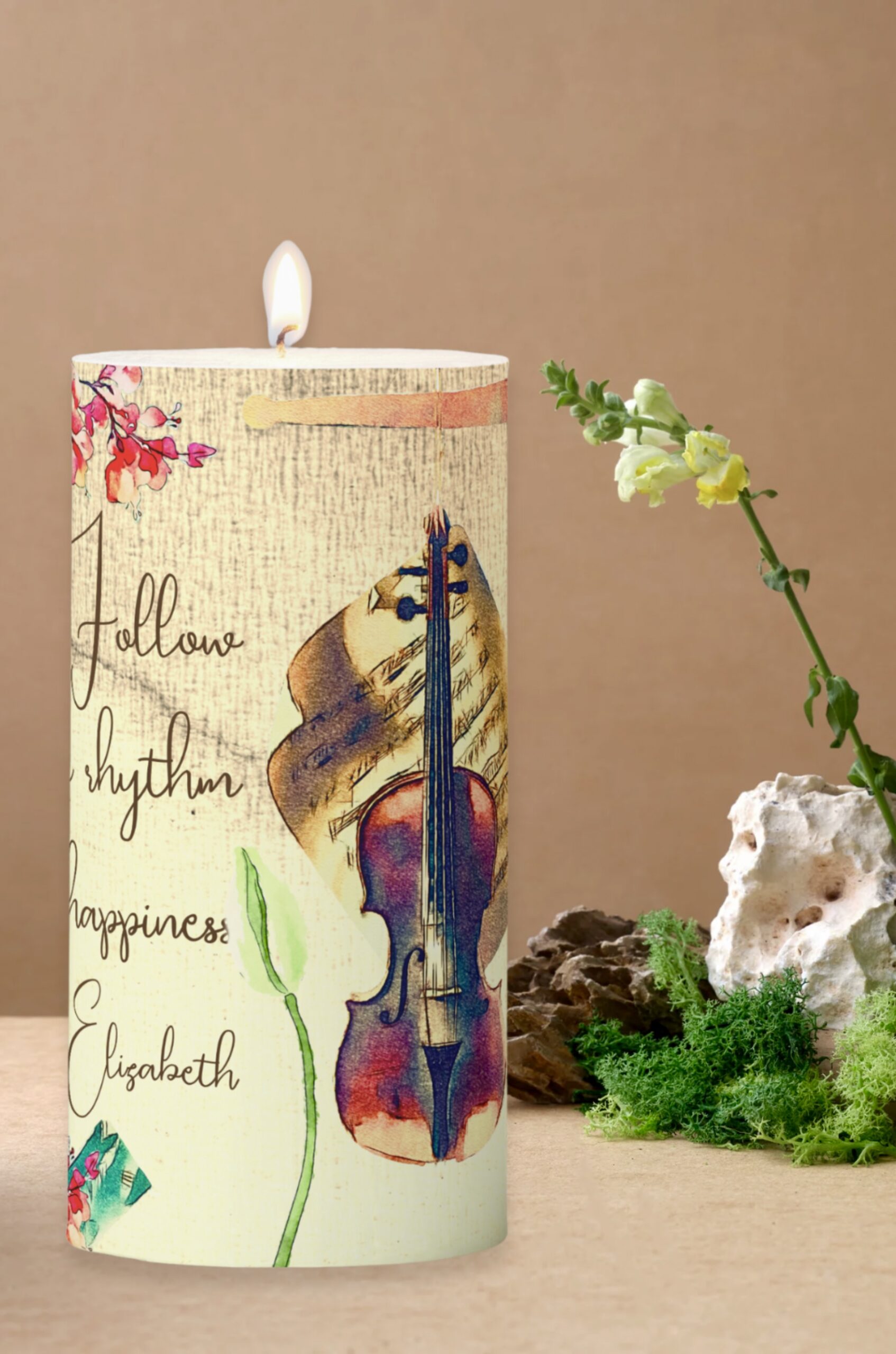 Pillar candle with violin and happiness message on a beige washed background.