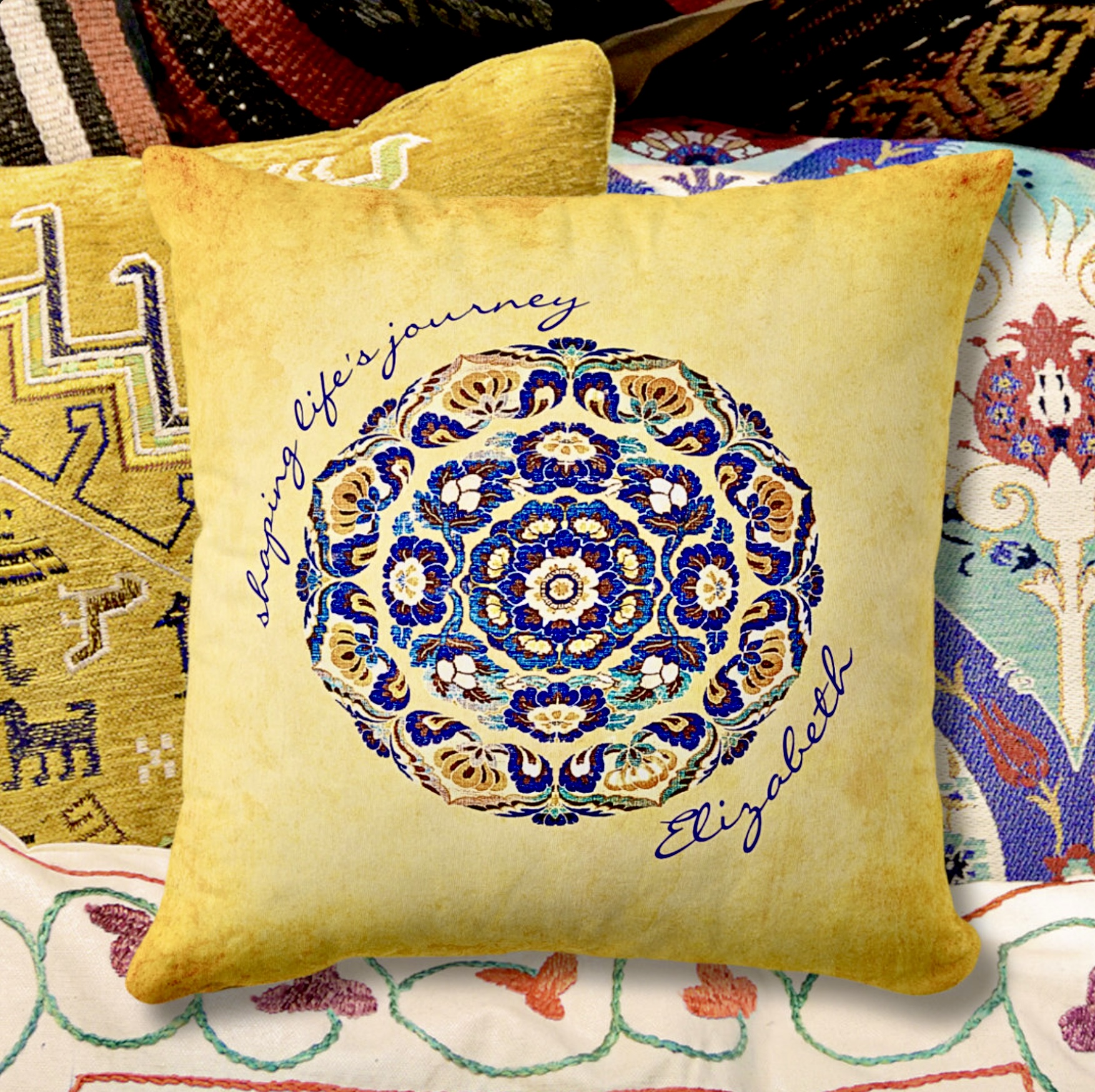 Fully customizable washed out mustard pillow with a blue flower medallion on the center, and inspirational message with a space for a name.