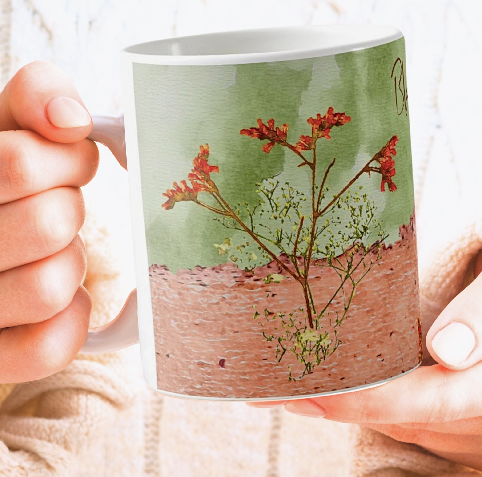 Closeup look of holding a green and peach coffee mug with flowers in orange and yellow colors.