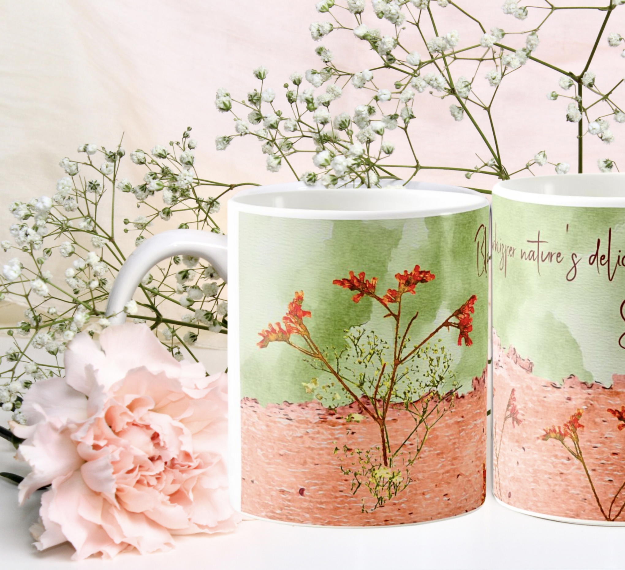 Two peach and green coffee mugs with an orange and yellow flowers design.