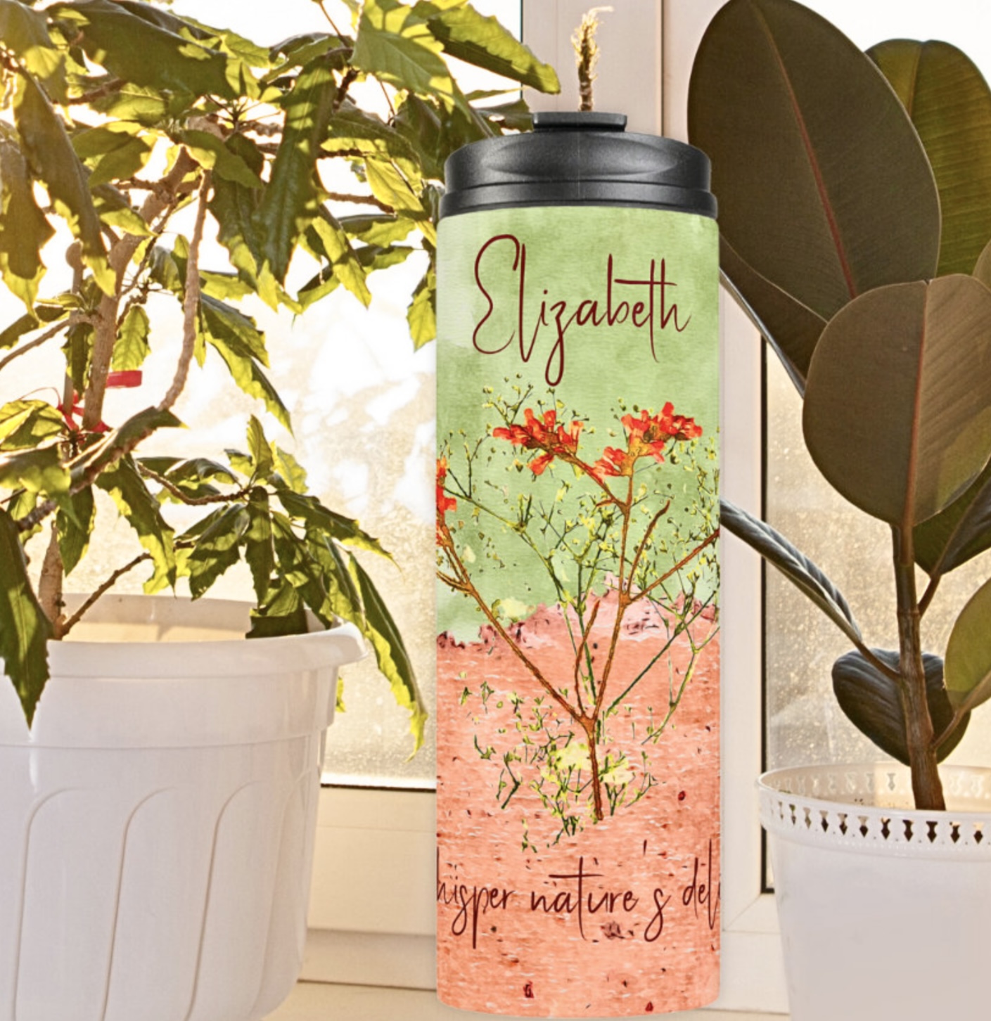 Peach and green tumbler with orange and yellow flowers by the window, surrounded by plants.