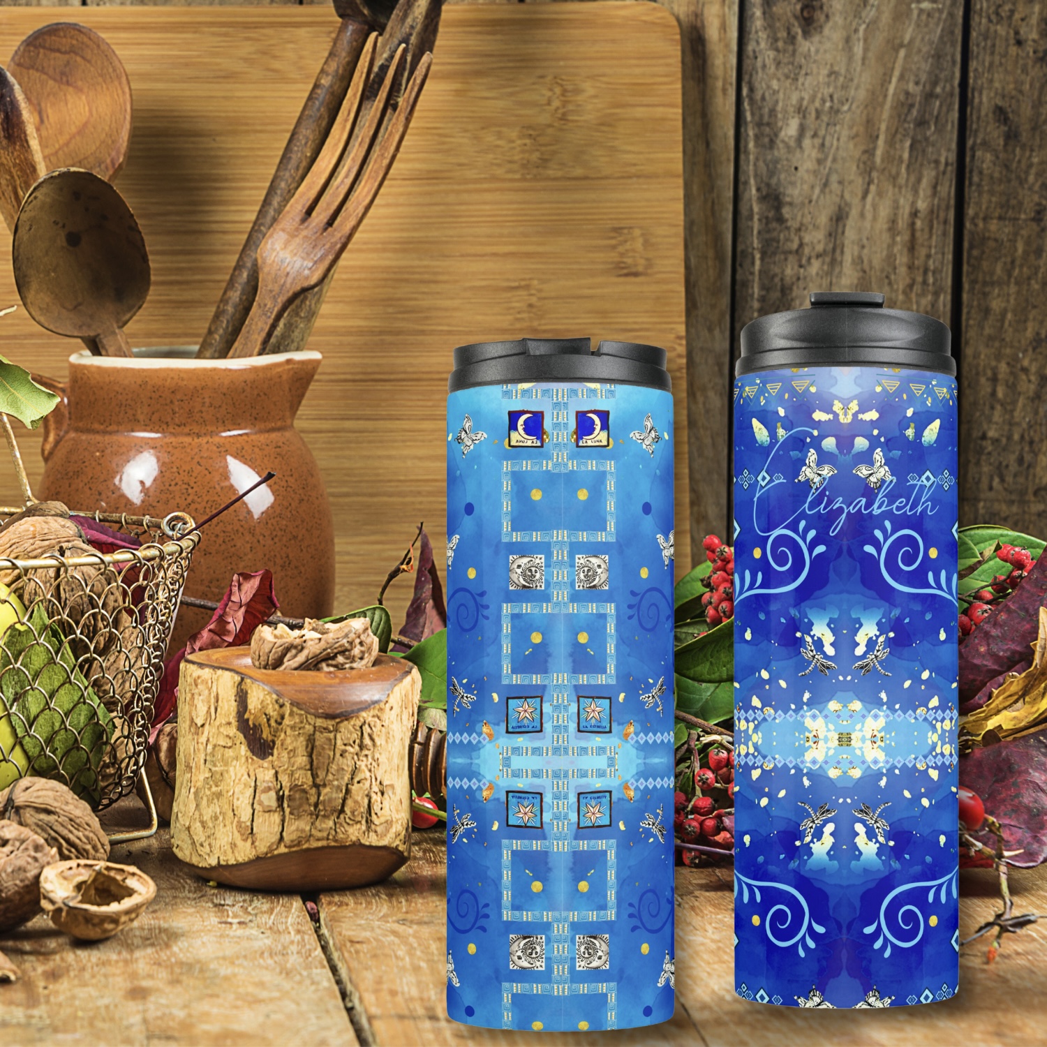 Two blue thermal tumblers with tribal design with Mexican motifs like heart charms, and silver dragonflies.