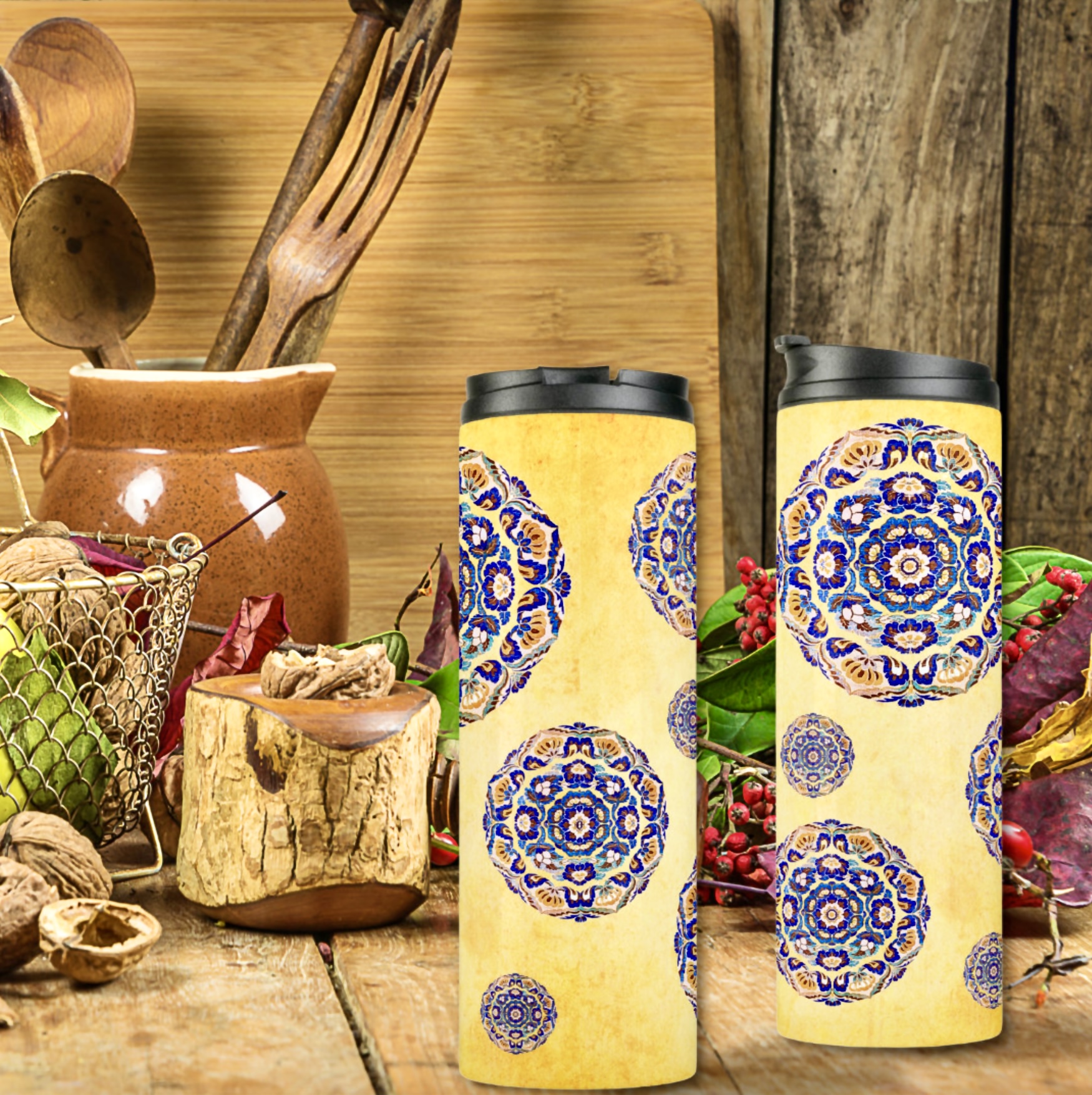 Two thermal tumblers with blue flowers medallions on a washed out yellow surface.