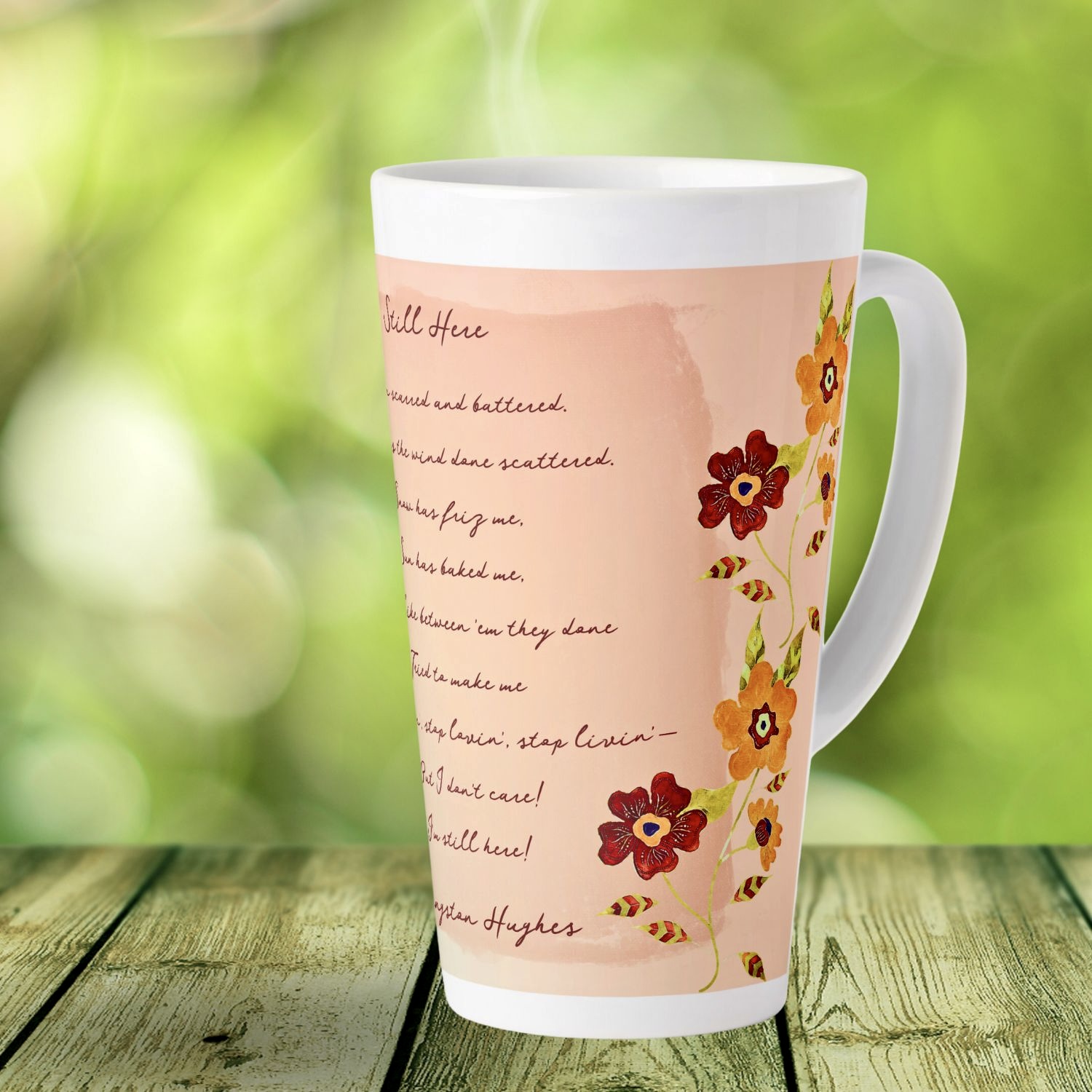 "Latte coffee mug featuring delicate watercolor flowers and a coral-toned mandala design, complemented by an excerpt from Langston Hughes' poem 'Still Here'."