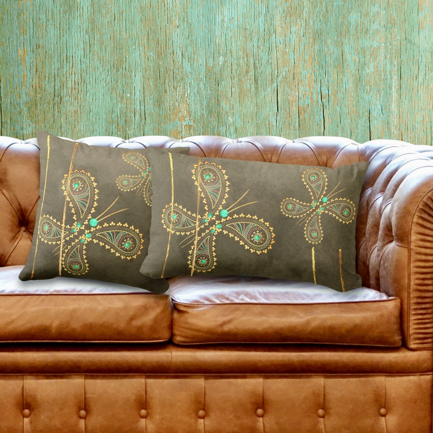 A cozy living room scene featuring a double-sided decorative throw pillow and lumbar pillow adorned with a teal and brown butterfly design, placed on a warm brown sofa. The intricate butterfly motifs in turquoise and golden hues stand out against the textured fabric of the pillows, adding a touch of whimsy and sophistication to the cozy ambiance of the space.