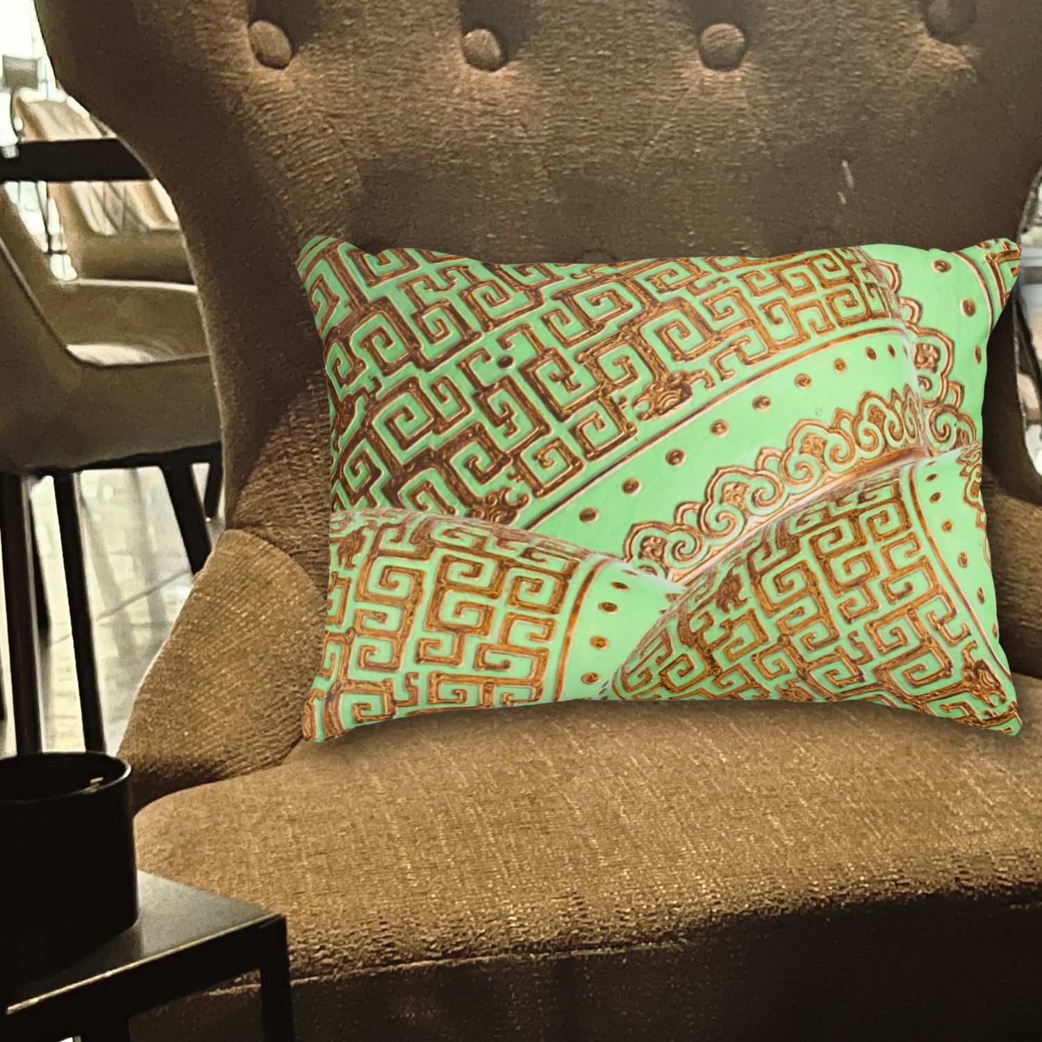 **ALT Text:**
Close-up of a vintage double-sided lumbar pillow featuring mint and gold pillows with green mint and gold vintage patterns, placed on a mustard color chair. The intricate designs and elegant color combination add sophistication and charm to the vibrant seating.